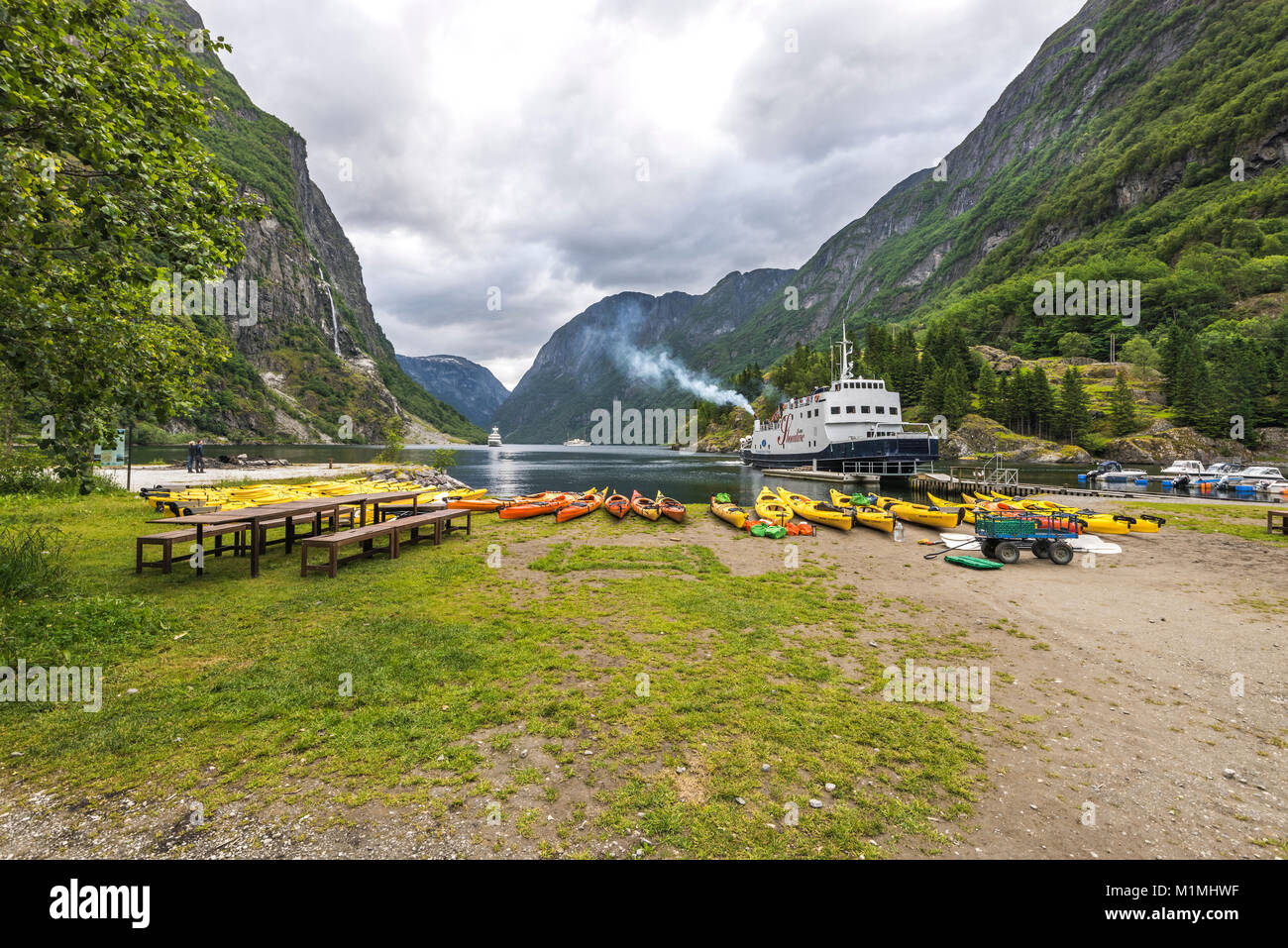 La baia di Gudvangen, riva del mare alla fine dell'Naeroyfjorden, Norvegia, Scandinavia, canoe preparati per la crociera del fiordo e un traghetto Foto Stock