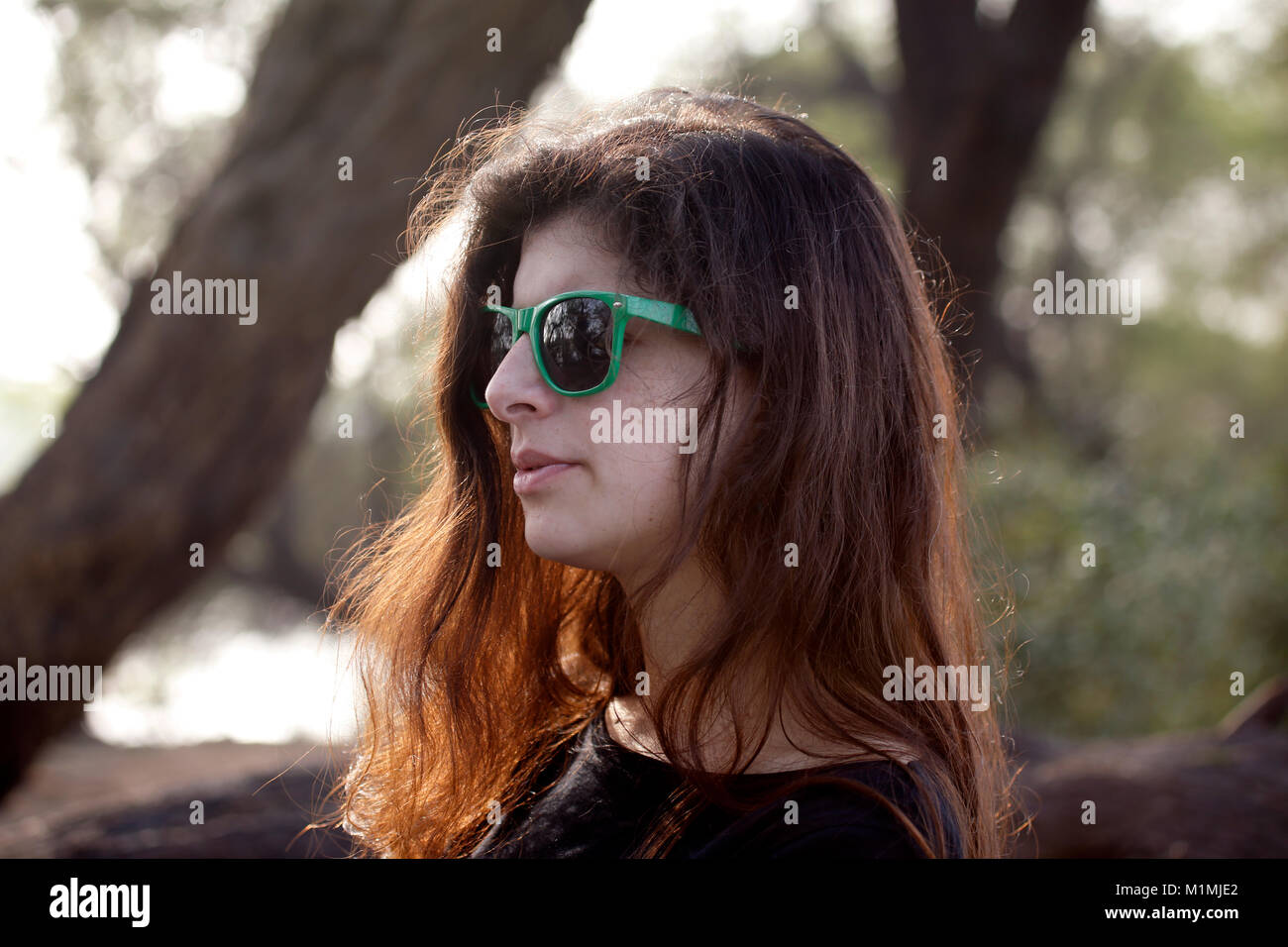 Ritratto di una donna in piedi all'aperto indossando occhiali da sole Foto Stock