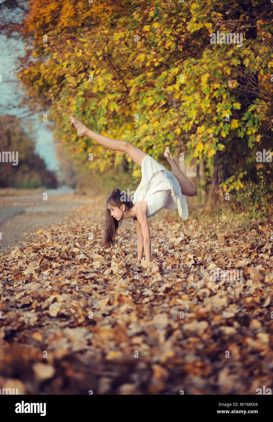 Ragazza in piedi capovolto in foglie di autunno fare yoga Foto Stock