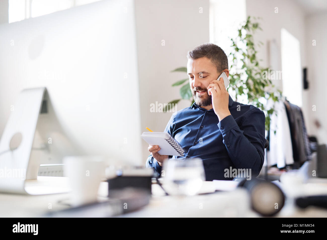 Imprenditore in sedia a rotelle con lo smartphone nel suo ufficio. Foto Stock
