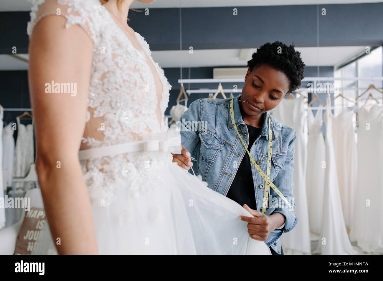 Professional abito da sposa designer montaggio abito nuziale alla donna nel suo negozio. Donna di effettuare le regolazioni di abito nuziale nella sua boutique. Foto Stock