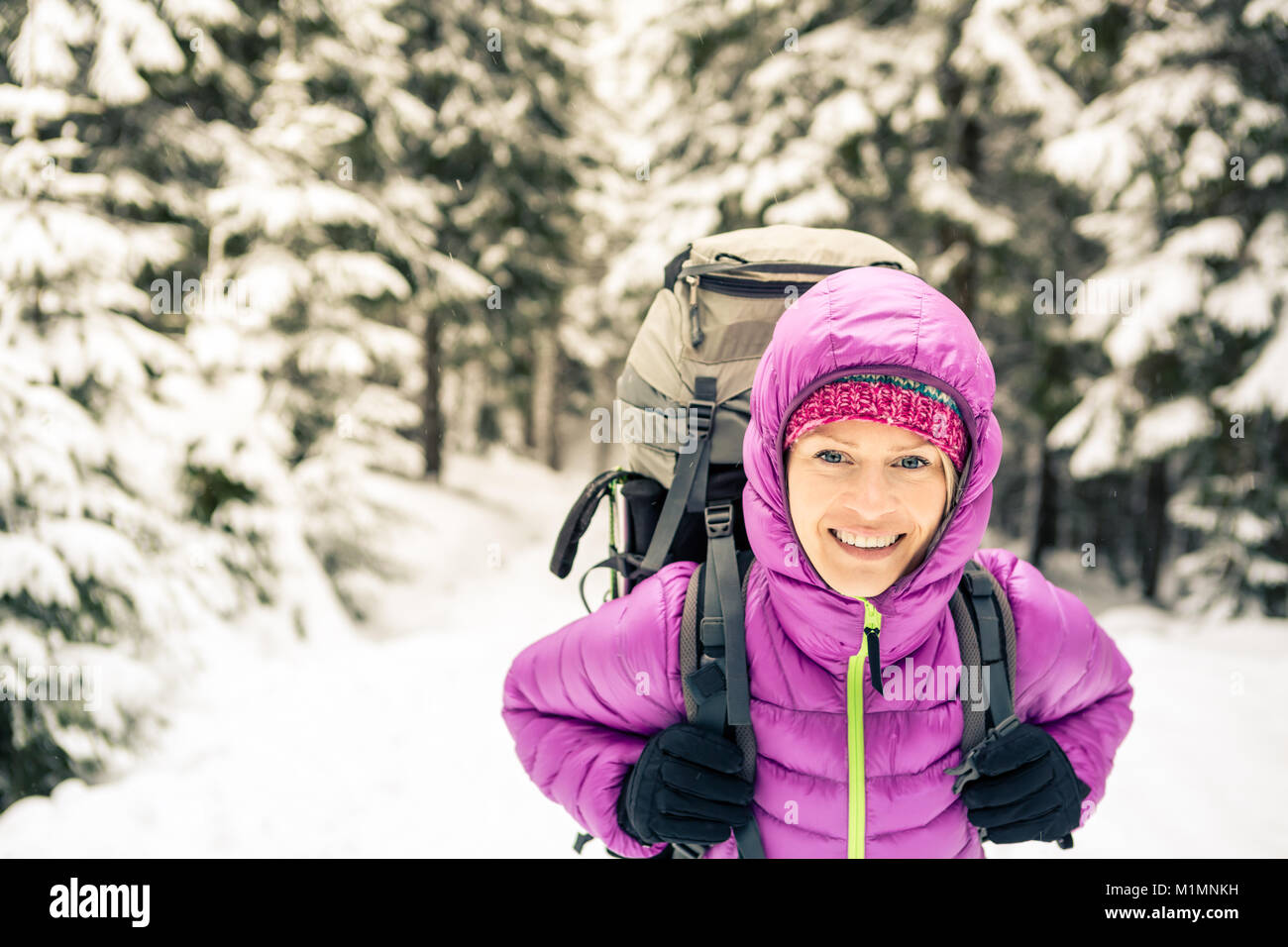Donna escursionismo in bianco inverno boschi della Foresta con zaino. Giovane ragazza camminare sul sentiero innevato. La ricreazione del fitness e uno stile di vita sano, camping all'aperto Foto Stock