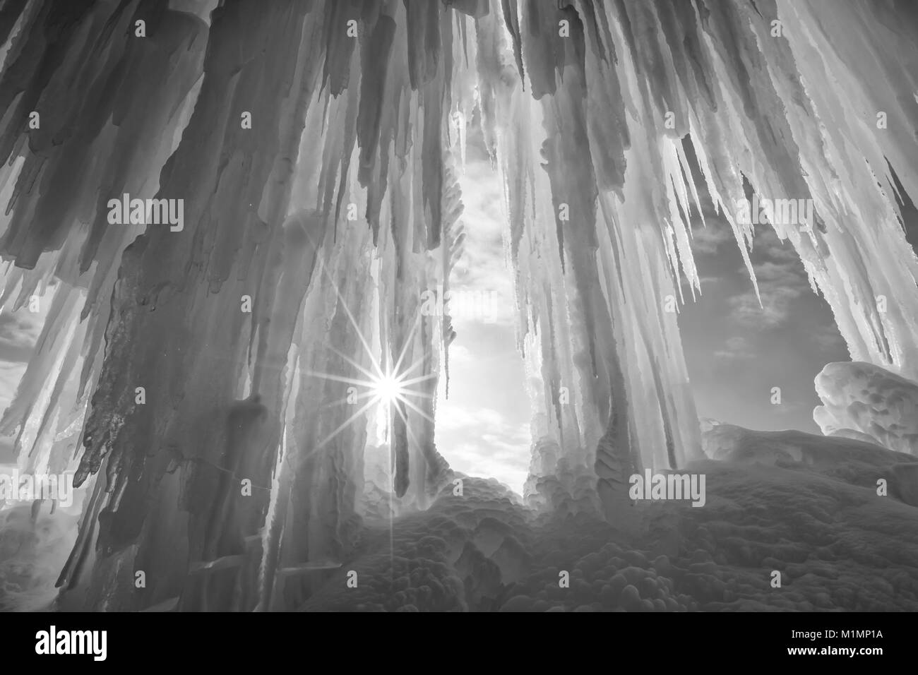 Un burst di sole risplende intorno ad una colonna di ghiaccio sipario sul Grand Island vicino Munising Michigan in inverno Foto Stock