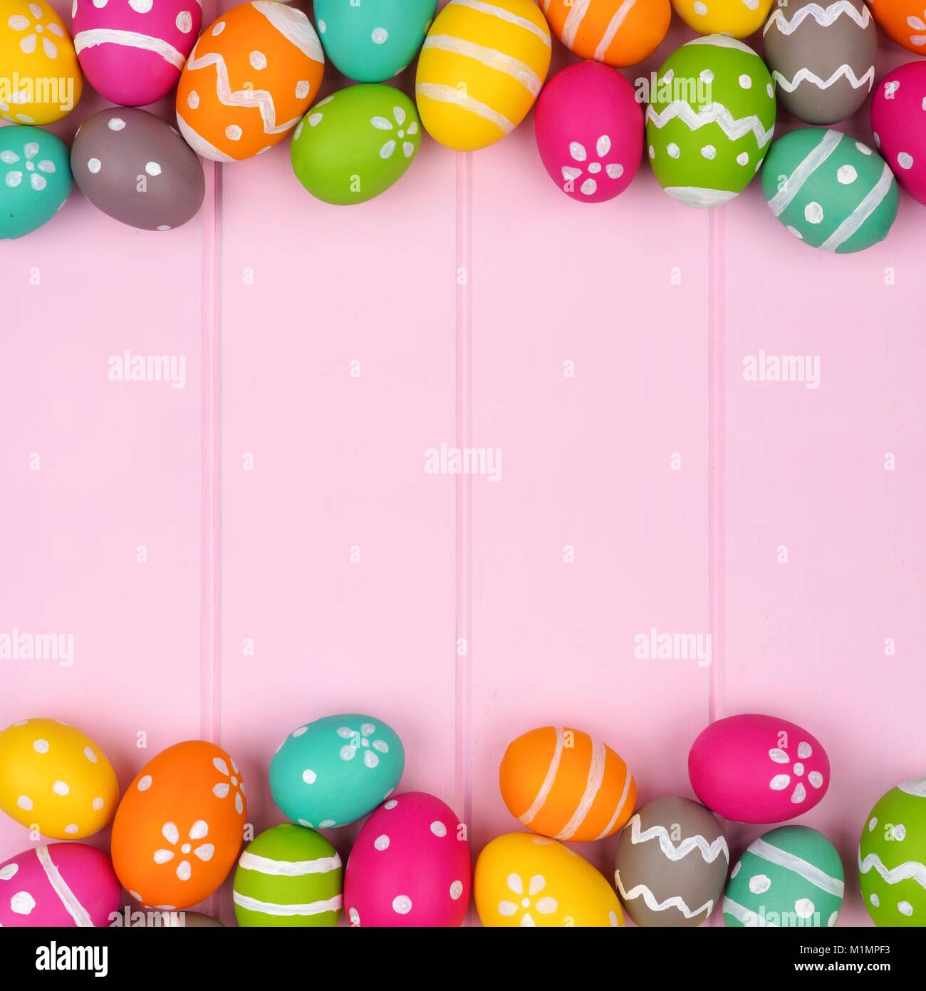 Coloratissimo uovo di pasqua doppio bordo contro una rosa di sfondo di legno Foto Stock