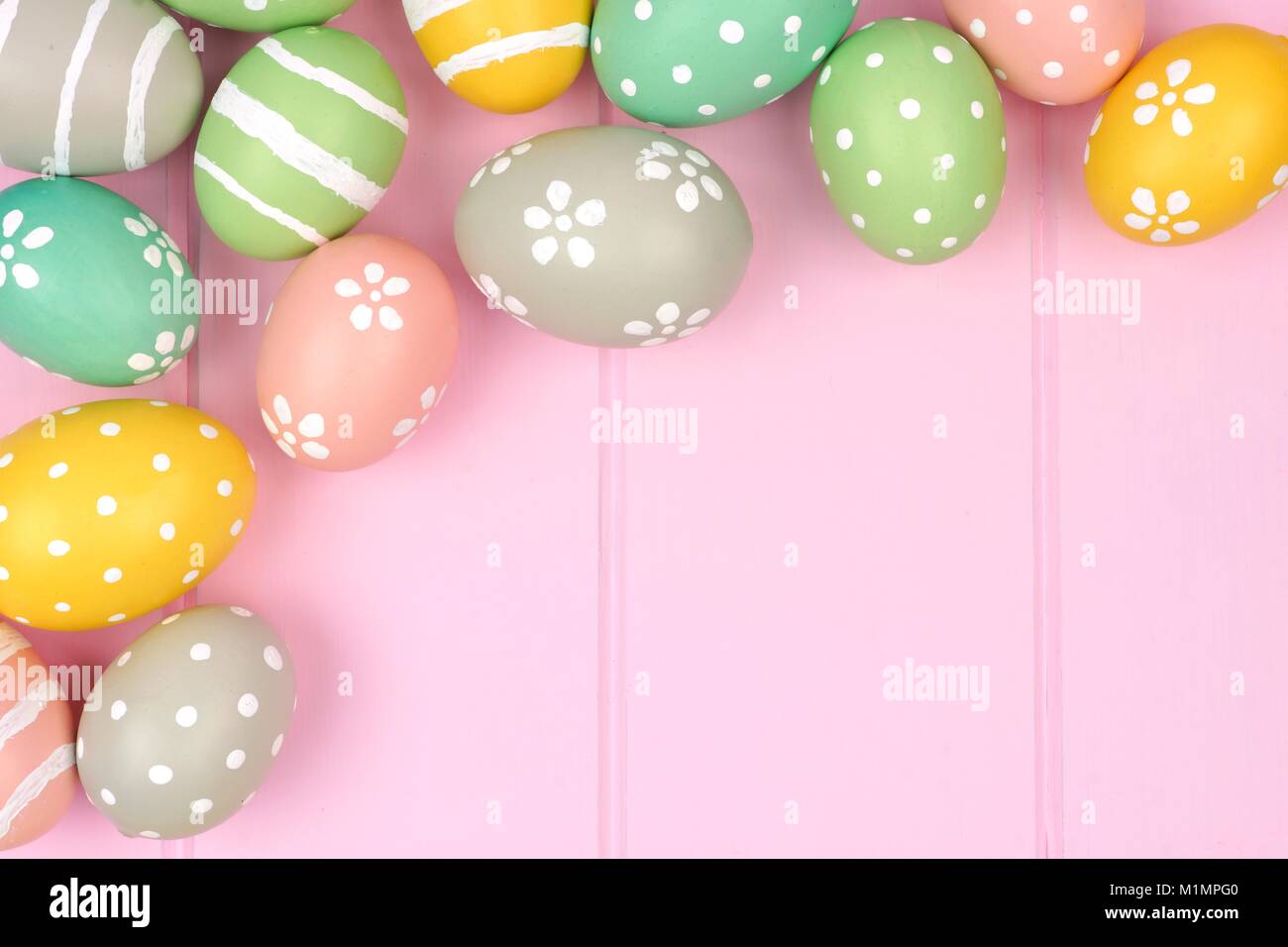 Pastello uovo di pasqua angolo bordo contro una rosa di sfondo di legno Foto Stock