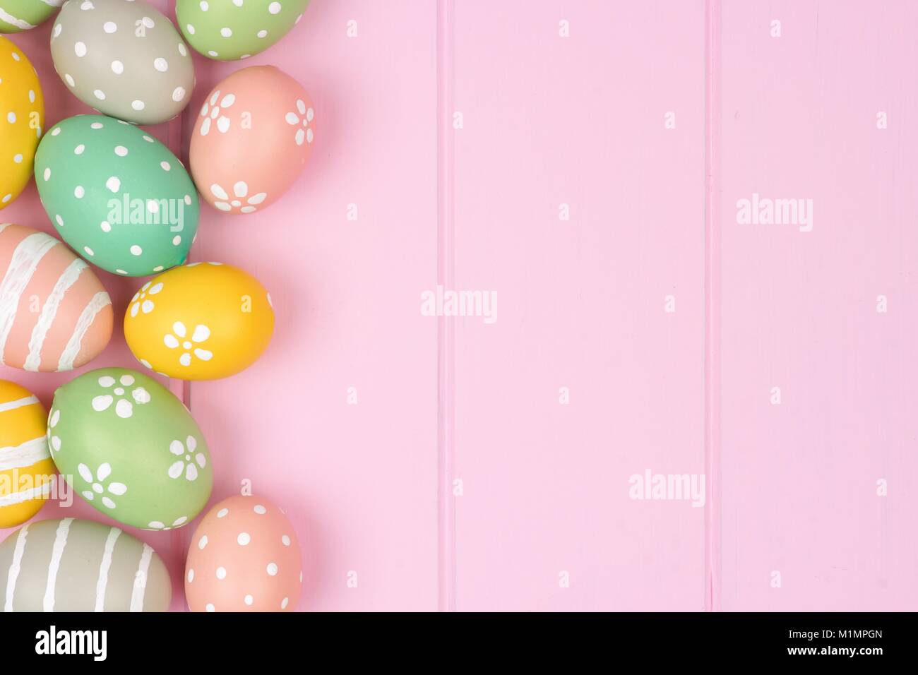 Pastello uovo di pasqua bordo laterale contro una rosa di sfondo di legno Foto Stock