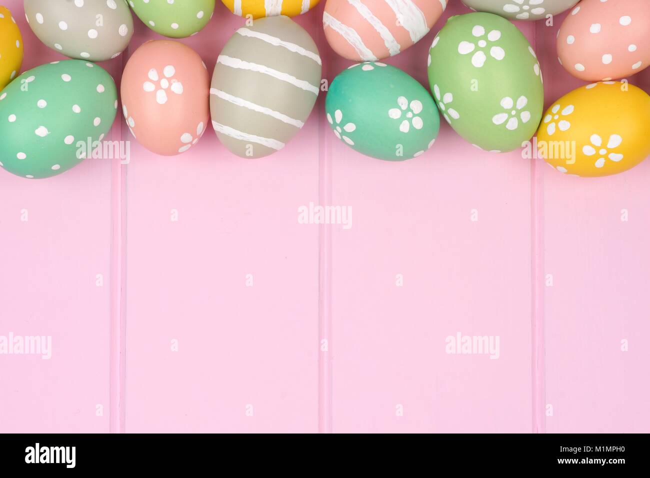 Pastello uovo di pasqua bordo superiore contro una rosa di sfondo di legno Foto Stock