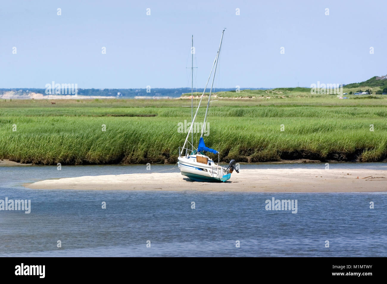'Alto e asciutto' una barca a vela arenati su una spiaggia di sabbia bar a bassa marea nel porto di roccia, Orleans, Massachusetts il Cape Cod Foto Stock