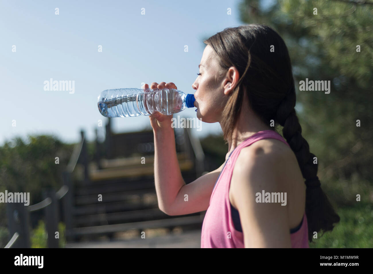 Donna di bere acqua da una bottiglia dopo l'esercizio. All'esterno. Foto Stock