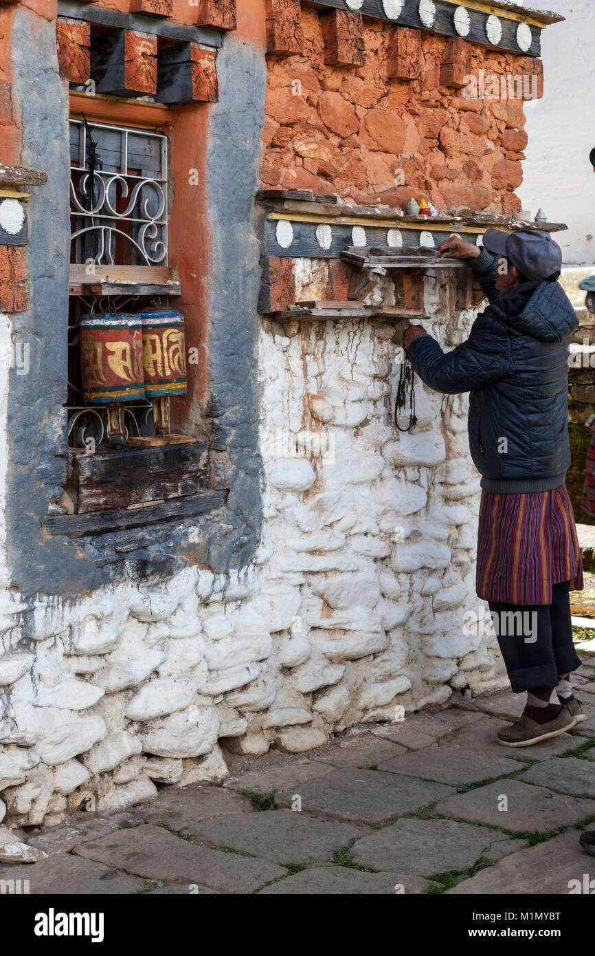 Bumthang, Bhutan. L uomo lo spostamento delle pietre a contare il numero di volte in cui egli ha filata Ruote della preghiera a Jambey Lhakhang tempio e monastero, vicino Jakar. Foto Stock