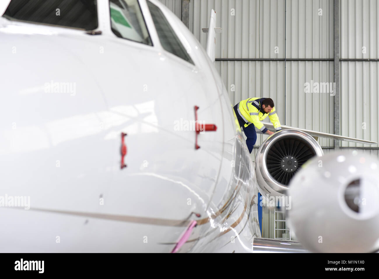Il personale di terra dell'aeroporto controlla la tecnologia e la sicurezza di un getto in hangar Foto Stock