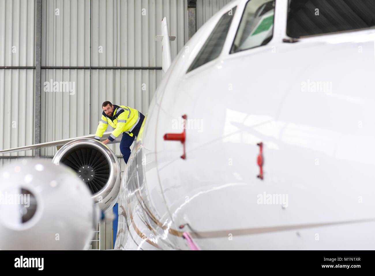 I lavoratori aeroportuali controllare un aereo per la sicurezza in un hangar Foto Stock