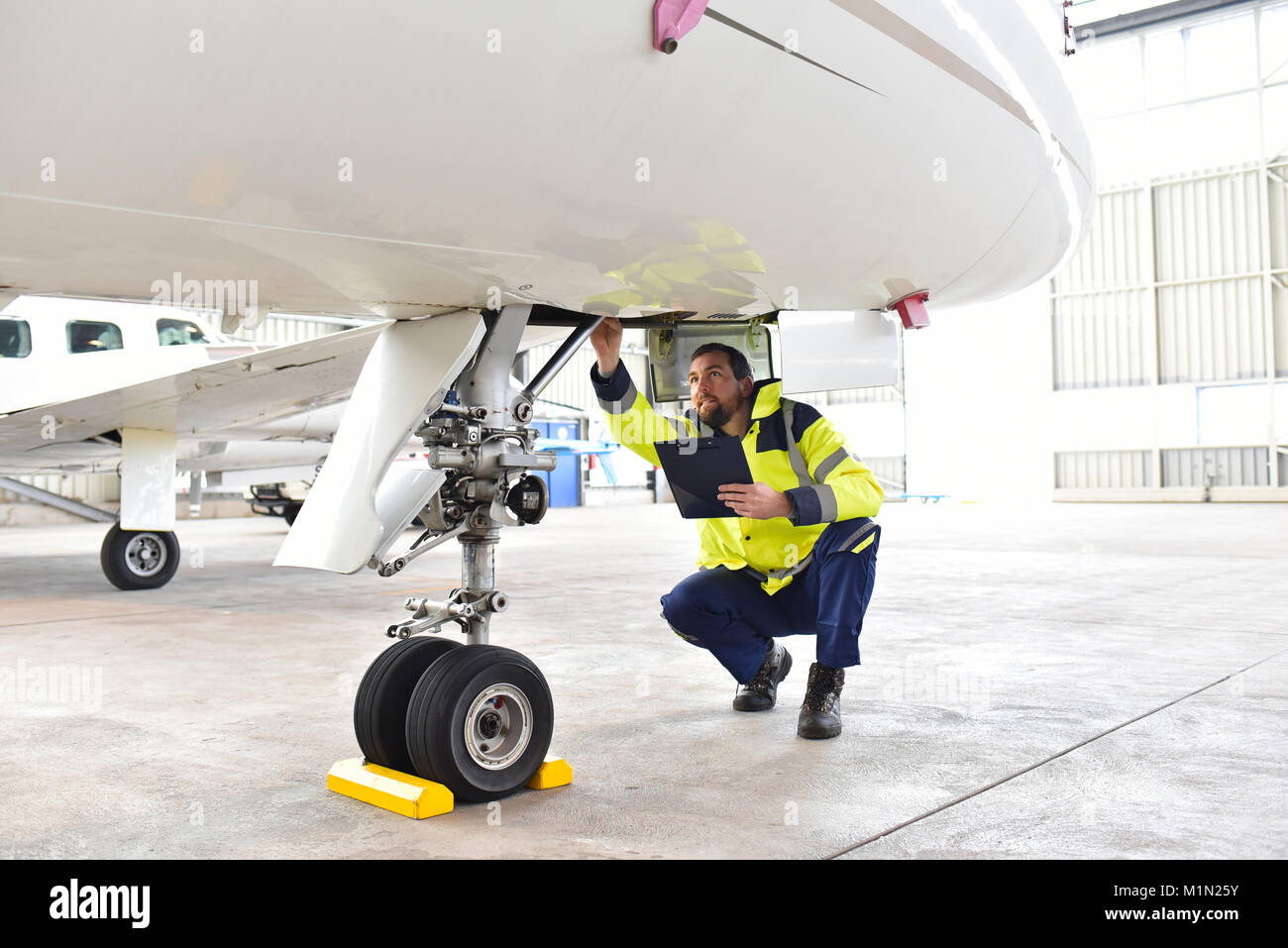 Personale di terra dell'aeroporto controllare il sistema idraulico del carrello di atterraggio degli aeromobili Foto Stock