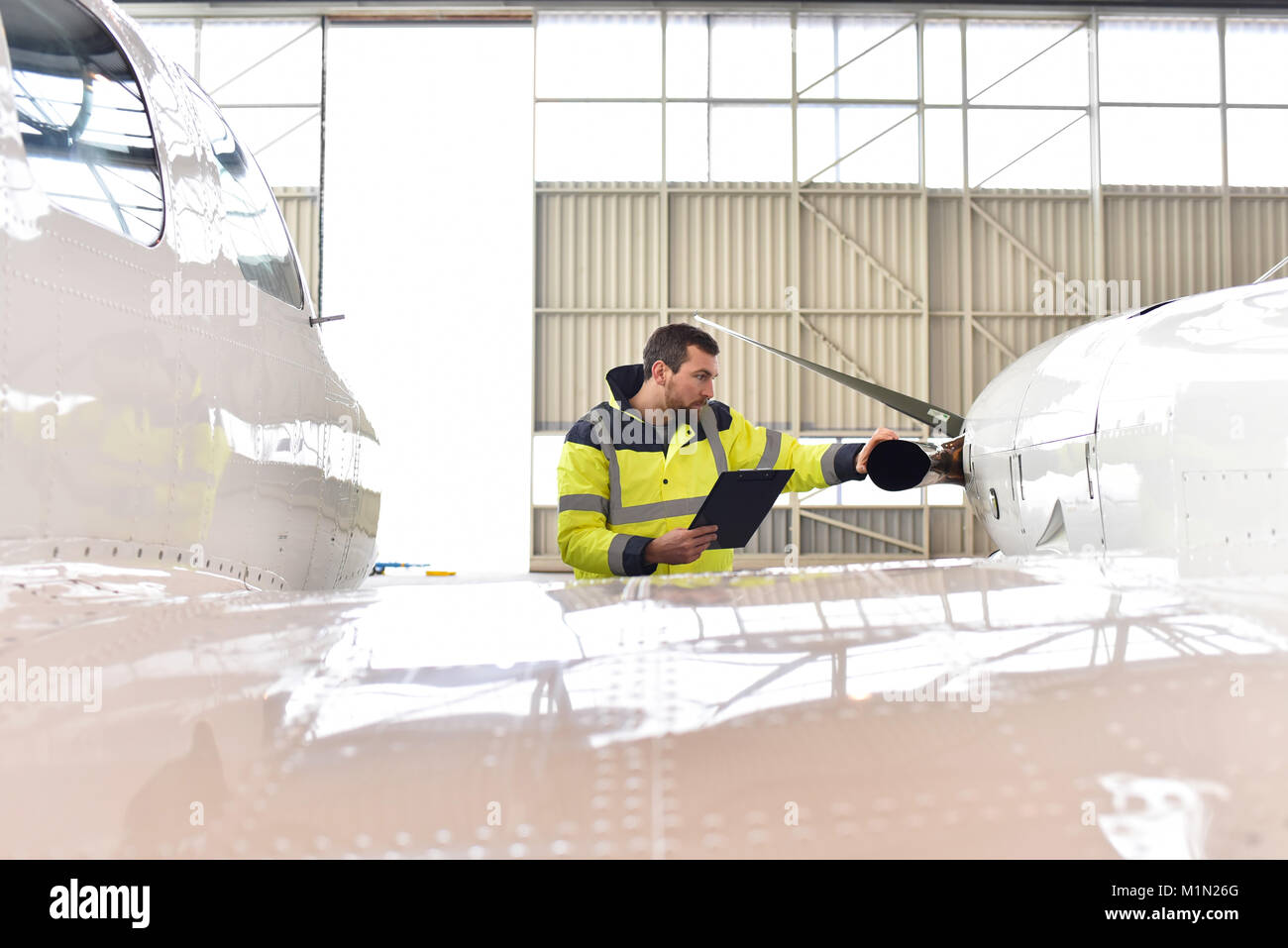 Meccanico aeronautico ispeziona e controlla la tecnologia di un getto in un hangar in aeroporto Foto Stock