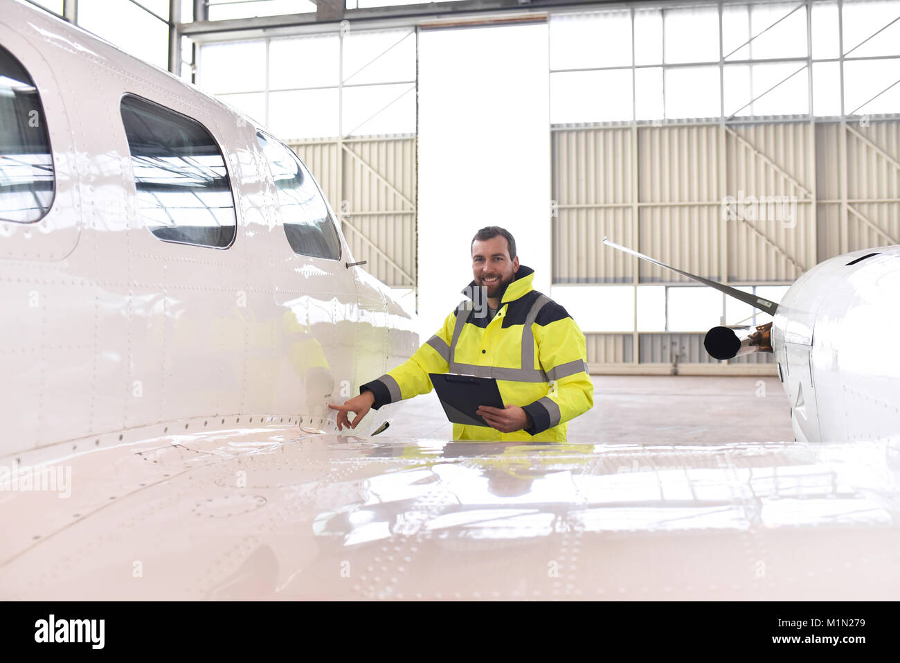 I lavoratori aeroportuali controllare un aereo per la sicurezza in un hangar Foto Stock