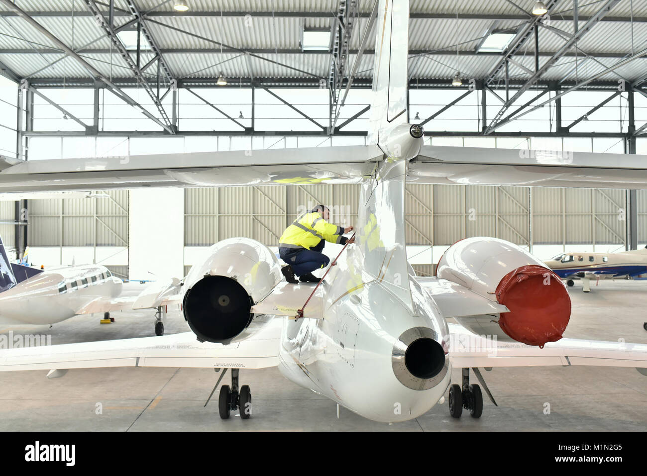 I lavoratori aeroportuali controllare un aereo per la sicurezza in un hangar Foto Stock