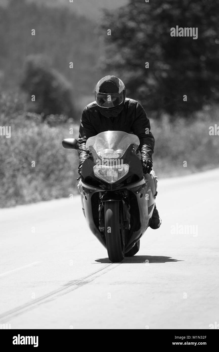 Bianco e nero rider sullo sport moto veloce nella strada di campagna Foto Stock