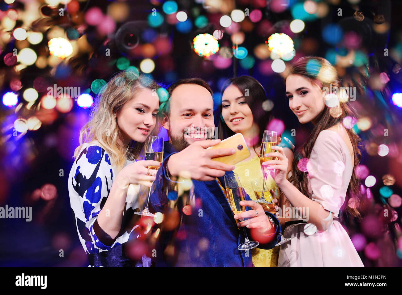 Amici stanno celebrando il caso, ridere, ballare e bere champagne Foto Stock