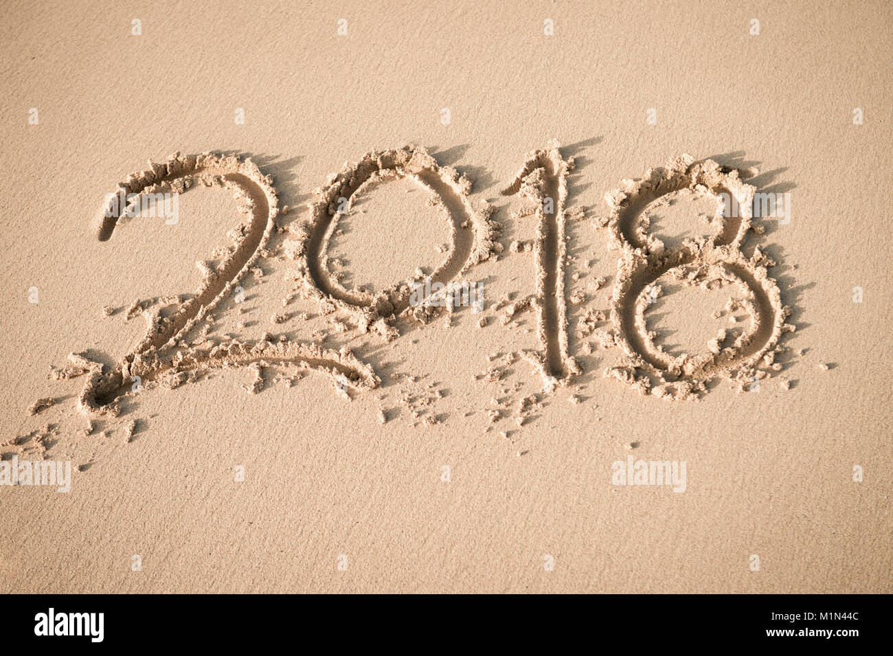 Nuovo anno 2018 messaggio manoscritta su una superficie liscia di spiaggia di sabbia soffice nella luce del sole di mattina Foto Stock