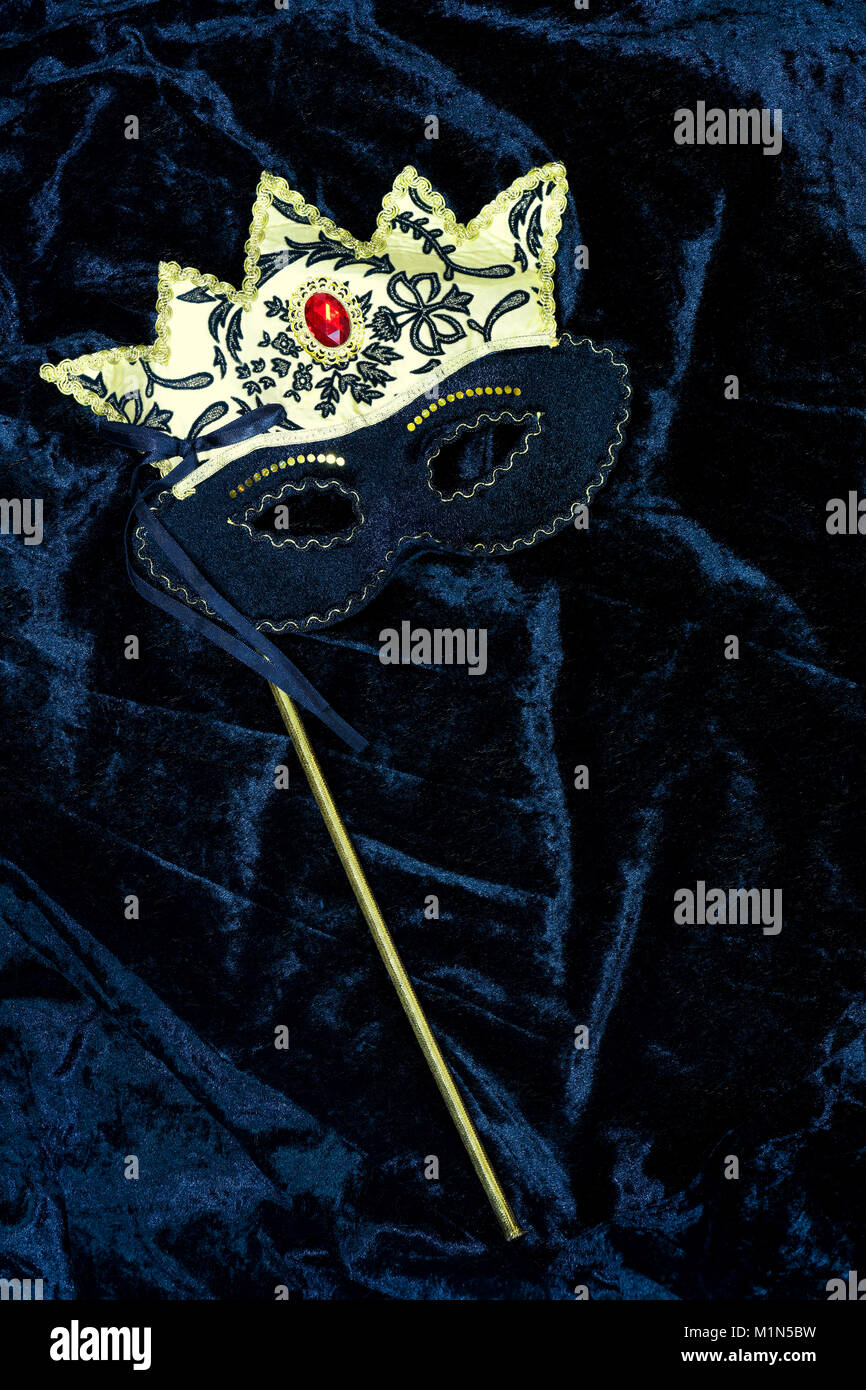 Oro maschera di Carnevale su un velluto nero sfondo , l'immagine verticale ideale per poster e spazio di copia Foto Stock