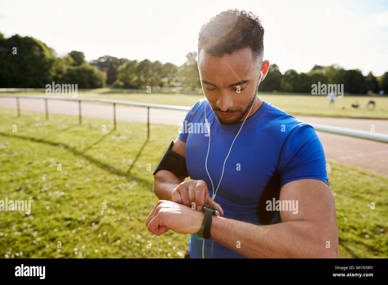 Giovane alla esecuzione di traccia impostazione app fitness su smartwatch Foto Stock