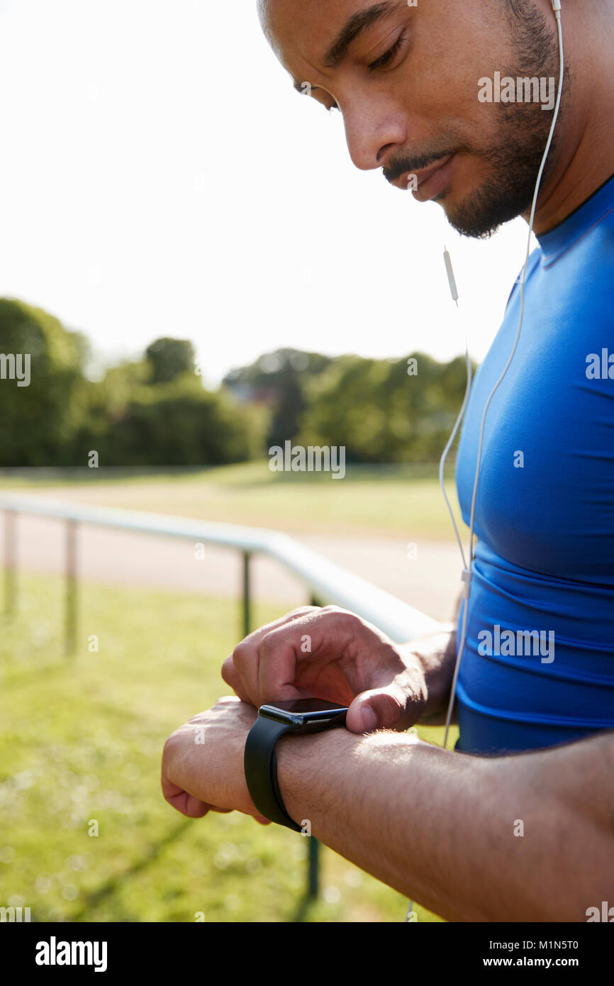 Atleta maschio in esecuzione di traccia impostazione smartwatch app Foto Stock