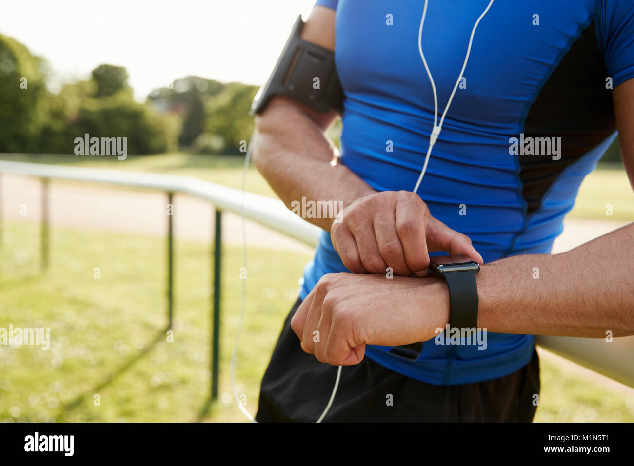Uomo al via l'impostazione app fitness su smartwatch, metà sezione Foto Stock