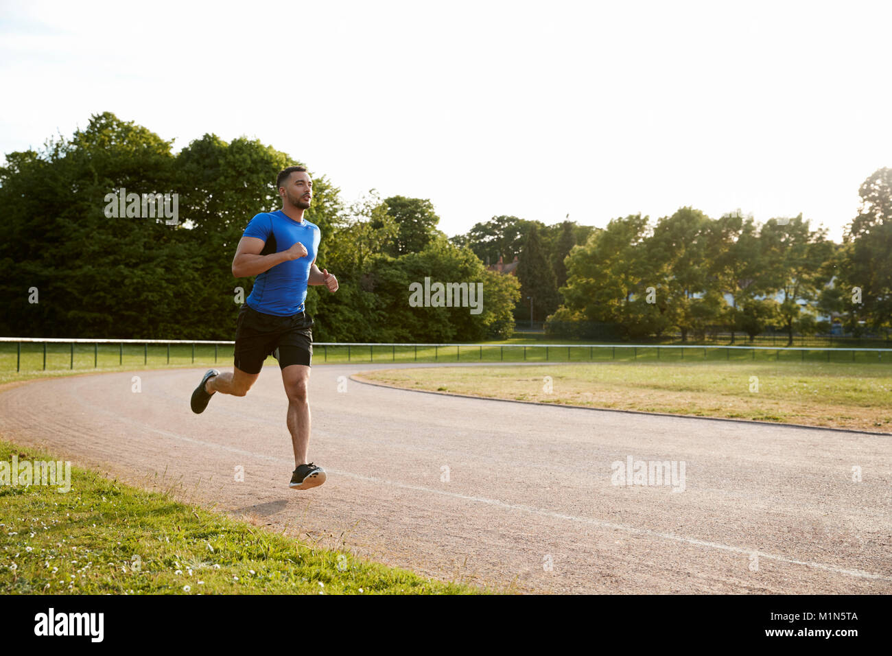 Giovane maschio atleta che corre in una pista a piena lunghezza Foto Stock