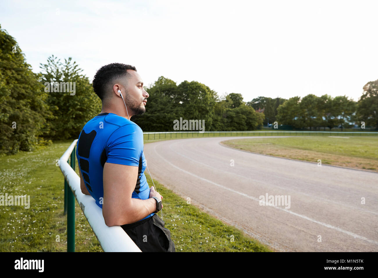 Voce maschile atleta che indossa gli auricolari prendere una rottura in corrispondenza di una via Foto Stock