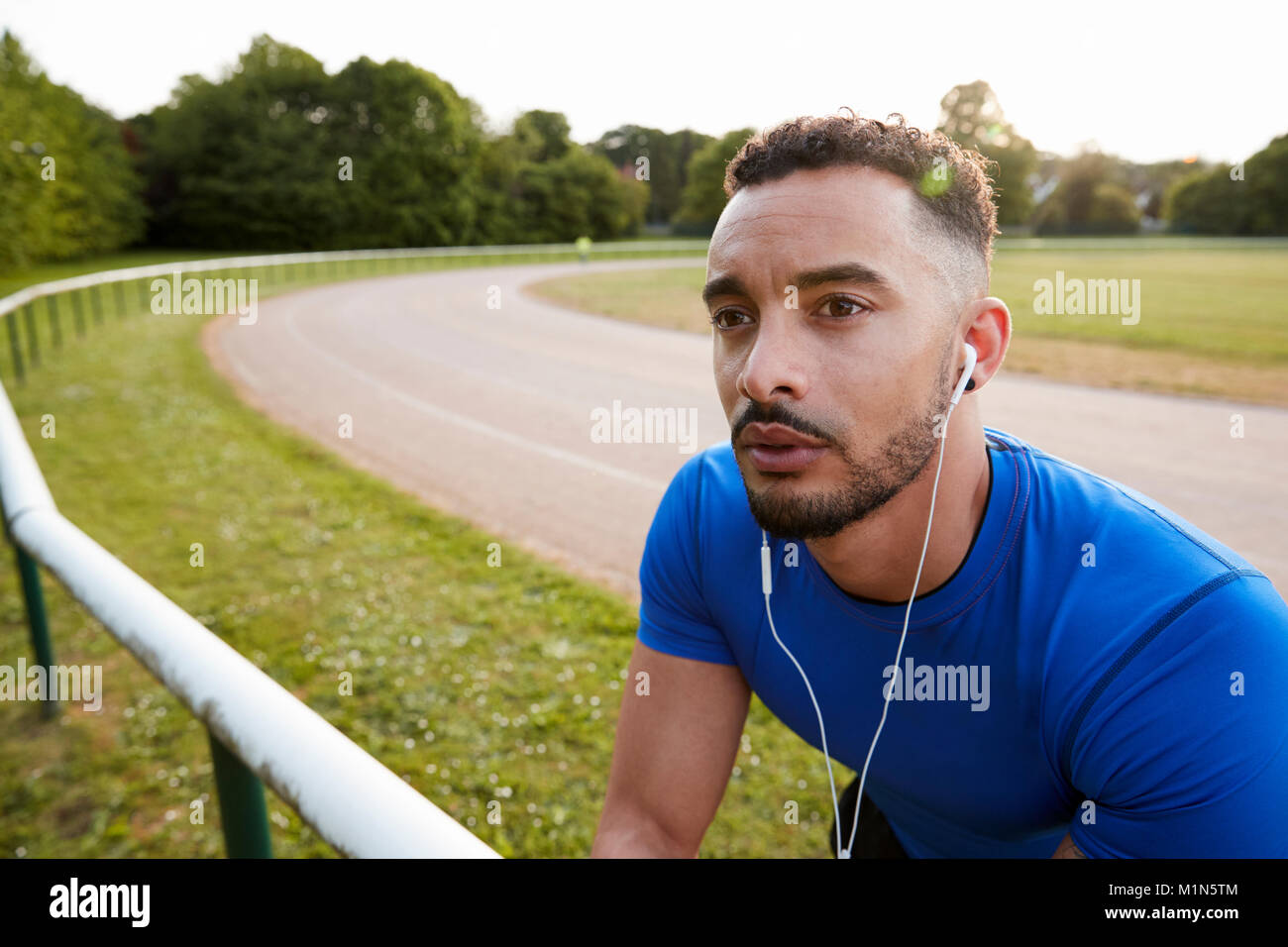 Voce maschile atleta che indossa gli auricolari alla via di corsa, close up Foto Stock