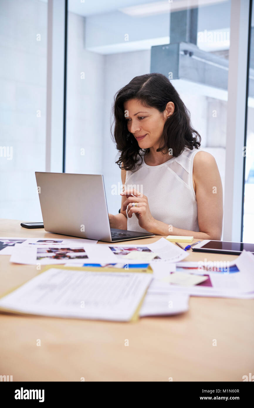 La donna in media creativi office utilizzando laptop, verticale Foto Stock