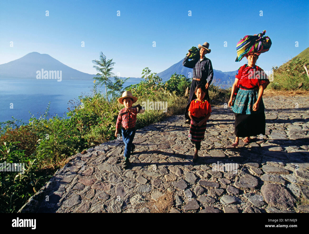 Guatemala. Panajachel. Lago de Atitlan. La famiglia di Maya per andare a casa dopo il lavoro sulla terra. Vulcano. Foto Stock