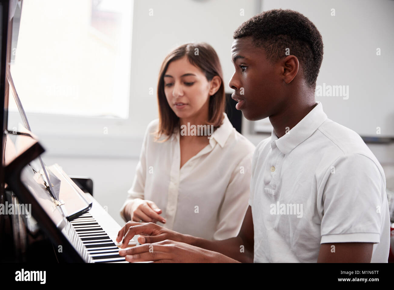 Pupilla d maschio con insegnante suonare il pianoforte nella lezione di musica Foto Stock