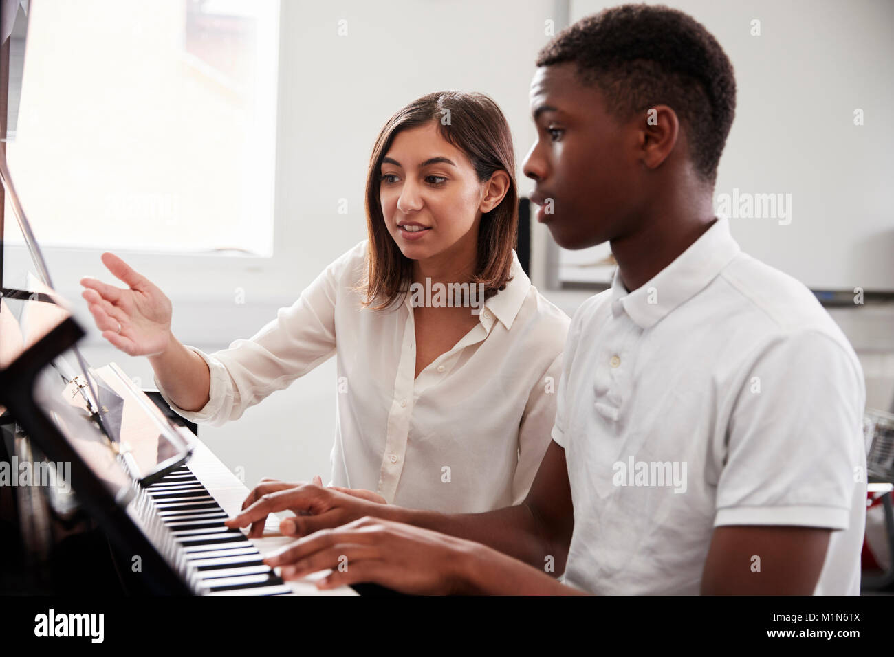 Pupilla d maschio con insegnante suonare il pianoforte nella lezione di musica Foto Stock