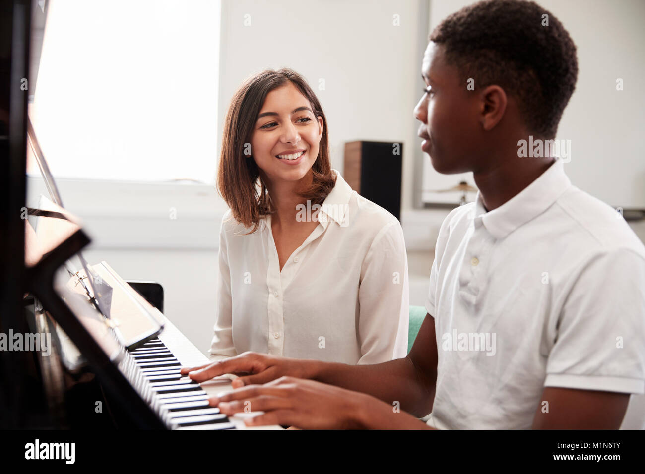Pupilla d maschio con insegnante suonare il pianoforte nella lezione di musica Foto Stock