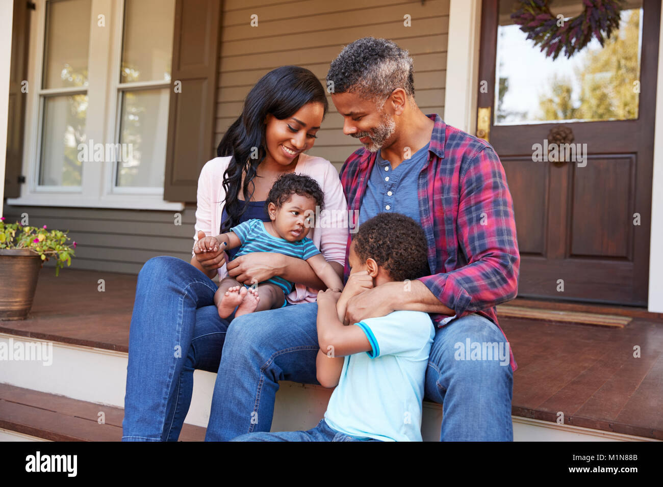 Famiglia con bambino figlio sedersi sulla scalinata che conduce al portico di casa Foto Stock