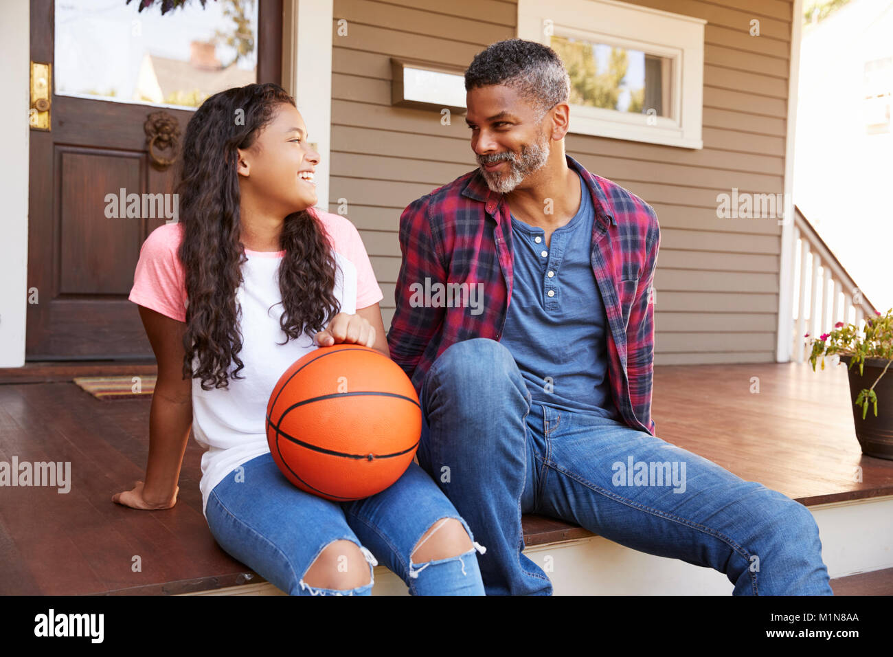 Padre e figlia discutendo la pallacanestro sul portico di casa Foto Stock