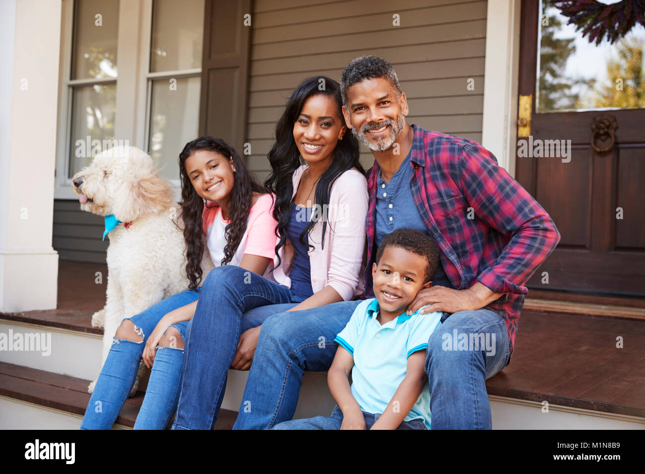 Famiglia con bambini e cane sedersi sui gradini di casa Foto Stock