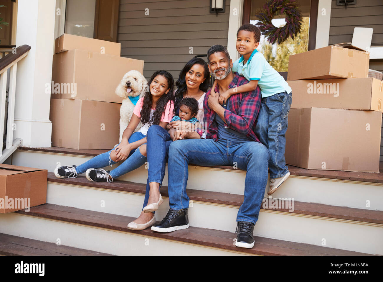 Famiglia con bambini e cane fuori casa sul giorno del trasloco Foto Stock