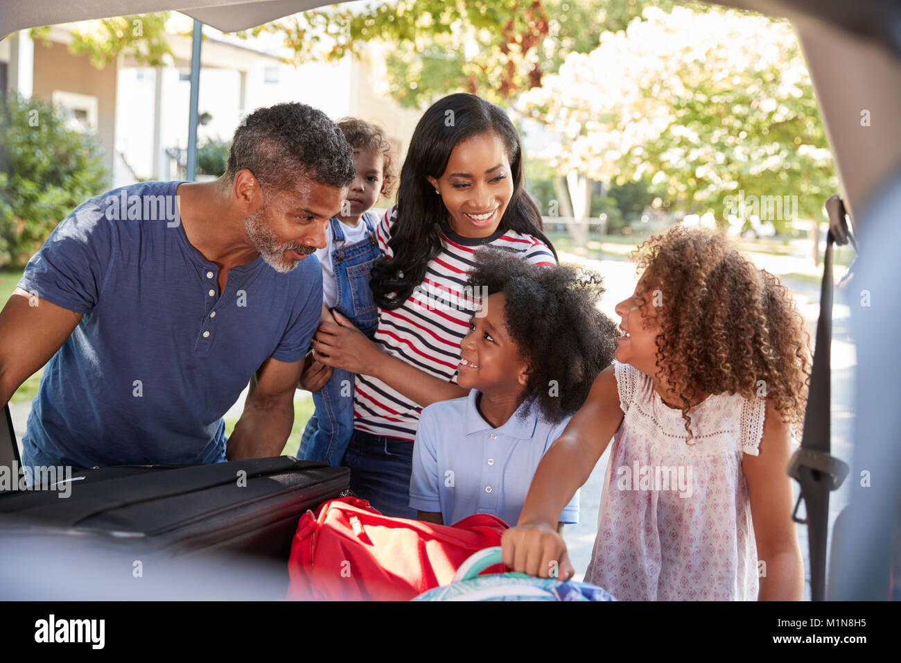 Lasciando la famiglia per la vacanza carico dei bagagli in auto Foto Stock