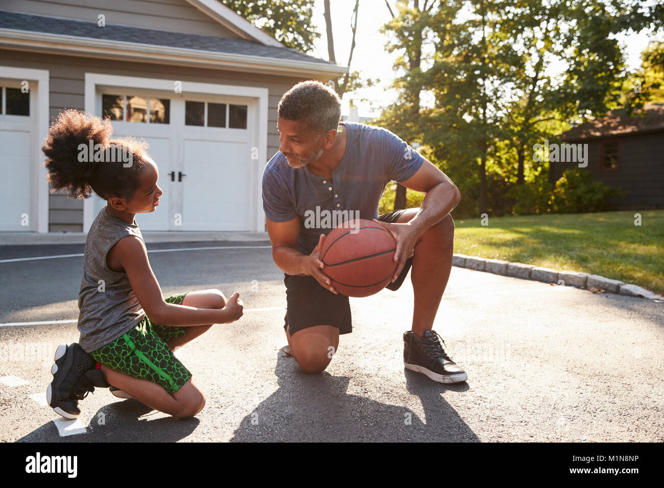 Padre figlio di insegnamento come giocare a basket sulla strada di casa Foto Stock