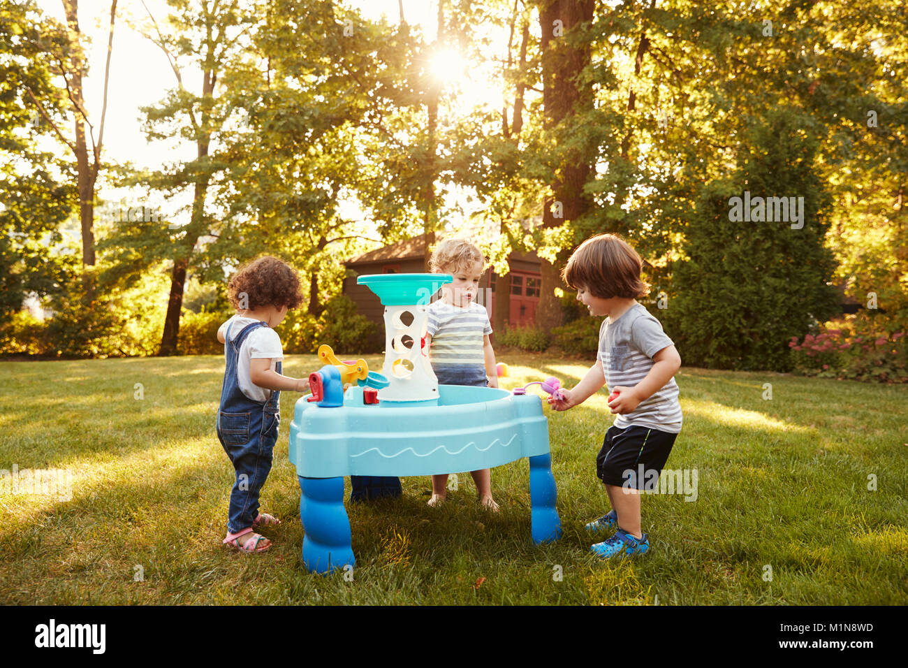 Gruppo di giovani bambini che giocano con la tavola di acqua in giardino Foto Stock