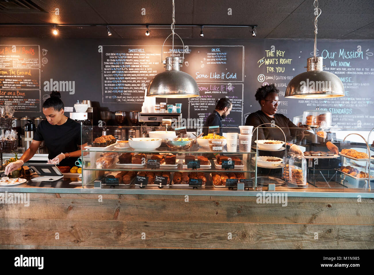 Il personale che lavora dietro il bancone in Busy Coffee Shop Foto Stock