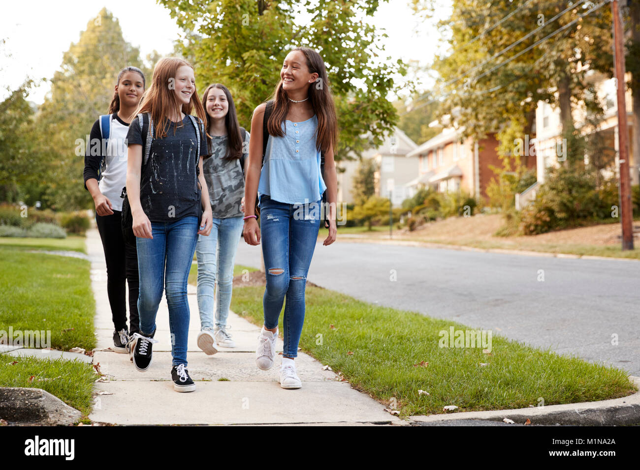 Quattro giovani teen ragazze andare a scuola a piedi insieme, vista frontale Foto Stock