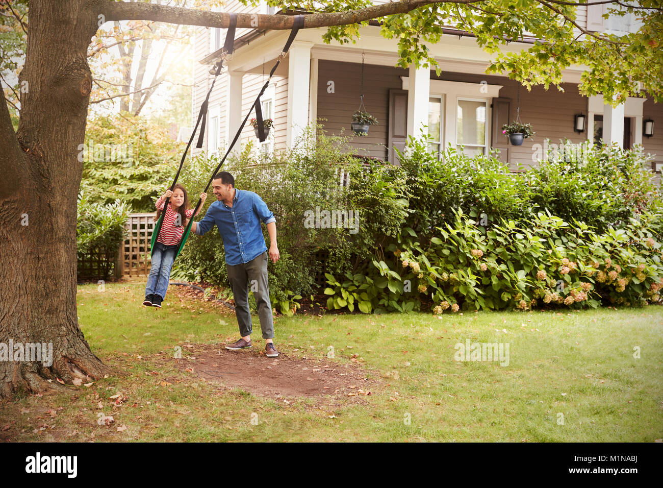 Padre Figlia di spinta su giardino Swing a casa Foto Stock