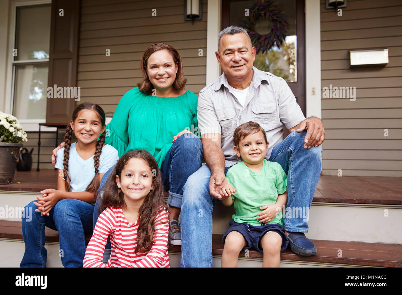 Nonni con i nipoti sedersi sulla scalinata che conduce fino alla Home Foto Stock