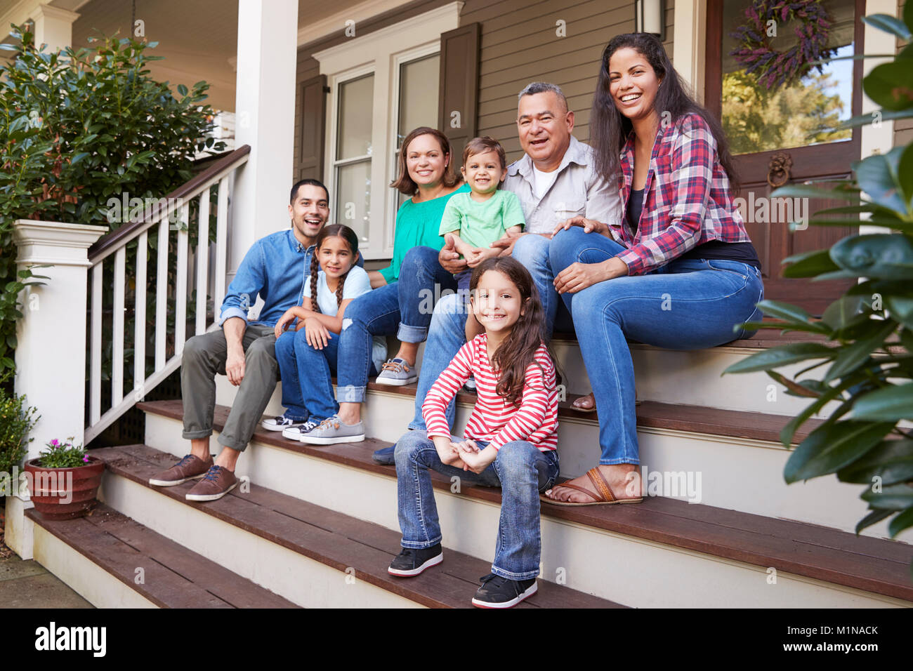 Multi generazione Famiglia sedersi sulla scalinata che conduce al portico della casa Foto Stock