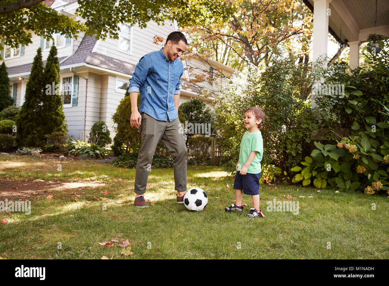 Padre giocava a calcio in giardino con figlio Foto Stock