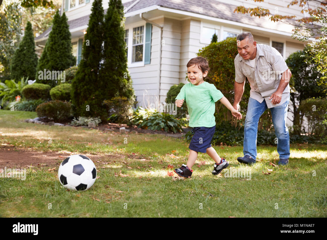 Nonno che giocano a calcio in giardino con il nipote Foto Stock