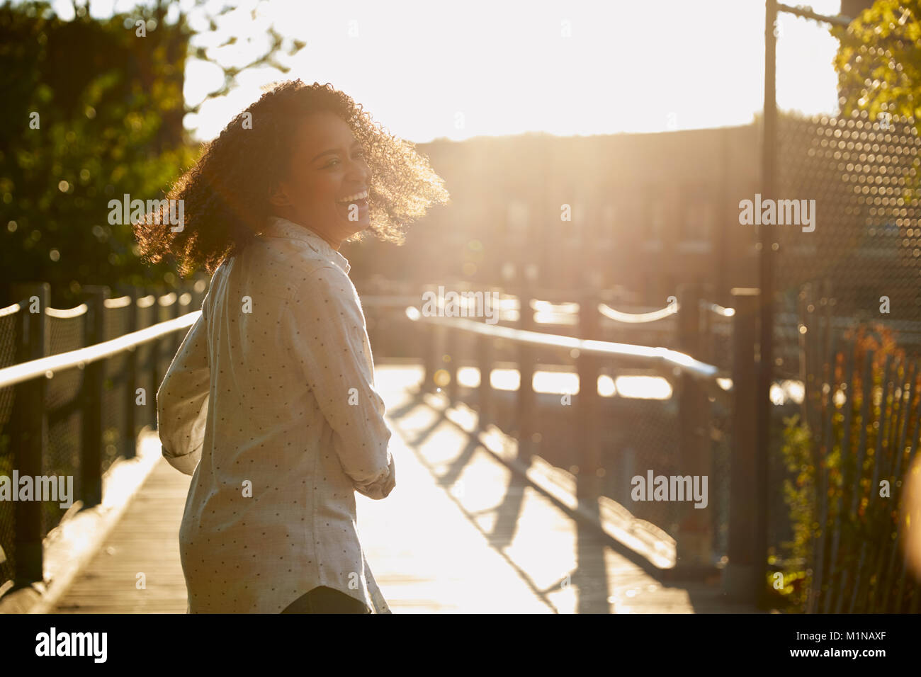 Giovane donna camminando lungo il ponte in contesto urbano Foto Stock